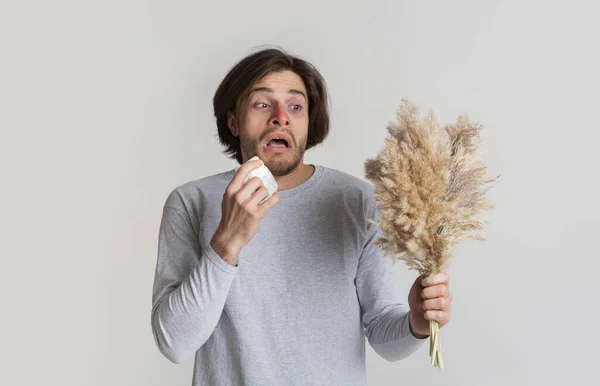 Man holds grass and sneezes in napkin — Stock Photo, Image