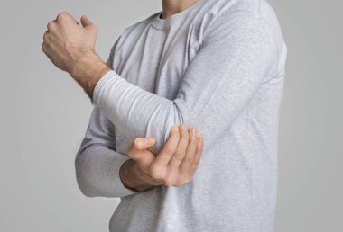 Adam gri arka planda acı veren dirseğe dokunur.