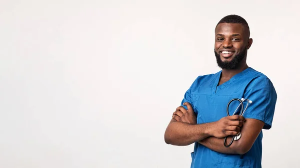 Cheerful black physician with stethoscope posing over white background