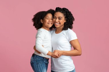 Mutlu siyah aile, anne ve kız, kameraya sarılıp gülümsüyor