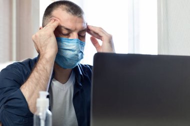 Dizüstü bilgisayardaki stresli adam evde oturan tapınaklara masaj yapıyor.