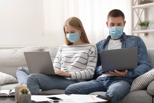 Young man and woman working on laptops at home