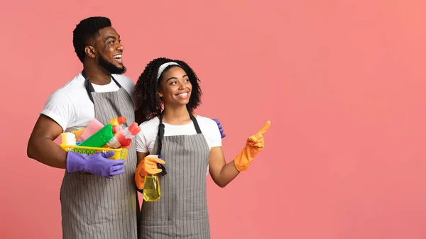Lächelndes Paar hält Korb mit Waschmitteln in der Hand und zeigt auf Kopierraum — Stockfoto