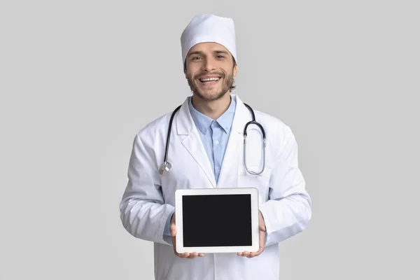 Cheerful doctor holding blank digital tablet in hands — Stock Photo, Image