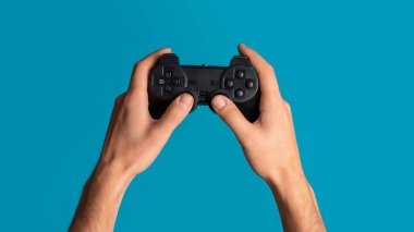 Kilitleme faaliyetleri. Milenyum adamı mavi arka planda video oyunu kontrolörünü tutuyor, yakın plan. Panorama