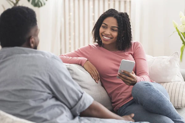 Young african couple chatting at home, relaxing on sofa together — Stock Photo, Image