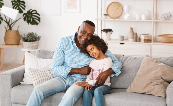 Fica em casa. Família afro-americana de avô e neta abraçando dentro de casa. Panorama — Fotografia de Stock