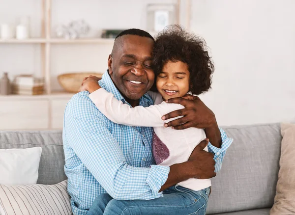 Fica em casa, sê feliz. Afro-americano avô abraçando sua linda neta na sala de luz — Fotografia de Stock