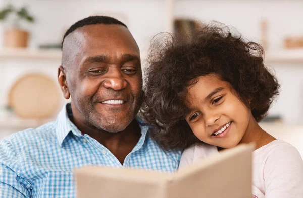 Aile kilitleri hobileri. Afrika kökenli Amerikalı bir çocuk dedesinin evde masal okumasını dinliyor. — Stok fotoğraf