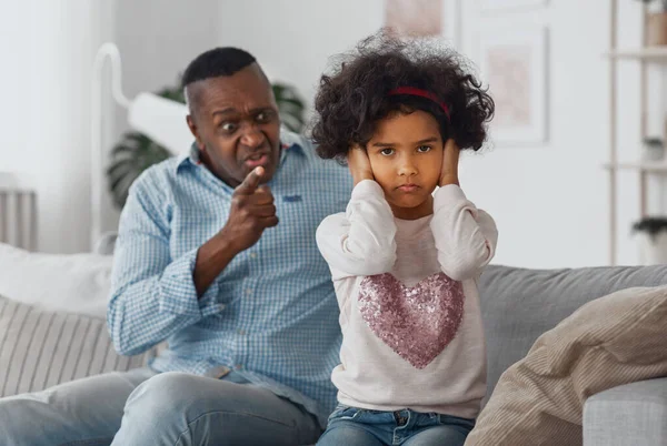 Arrabbiato nonno afroamericano urla contro sua nipote a casa, concentrarsi sulle orecchie di chiusura bambino — Foto Stock