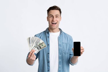 Adamın elinde dolar ve boş ekranlı akıllı telefon var.