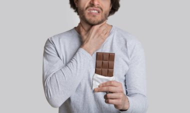 Çikolataya alerjisi var. Adam boğazını tuttuğu için kötü hissediyor.