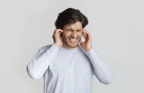 Concepto de dolor de oído. Guy muecas y toca las orejas — Foto de Stock