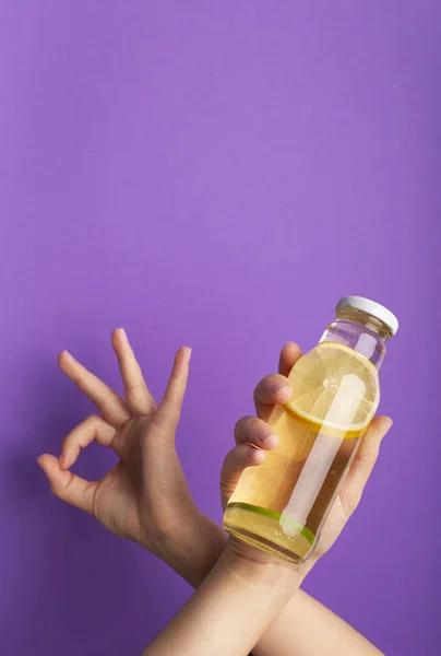 Frau zeigt Ok und Flasche Detox-Wasser mit geschnittener roher Zitrone — Stockfoto