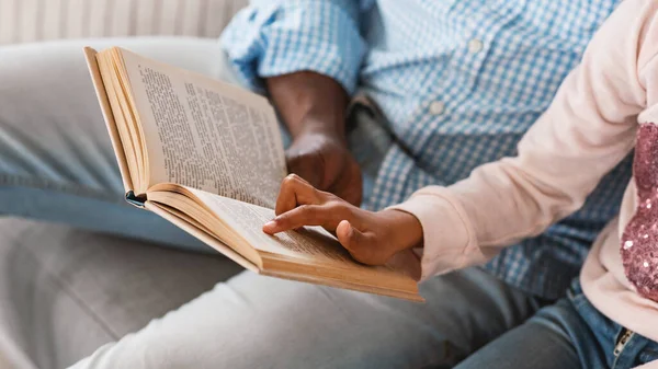 Rimani a casa. Lillte ragazza afroamericana leggendo fiaba con il nonno, primo piano delle mani che tengono libro — Foto Stock