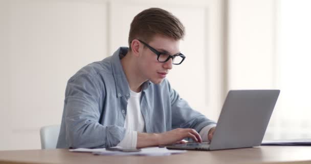 Mladý chlap sledování výuky on-line na notebooku v domácí kanceláři — Stock video