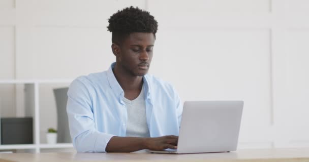 Young african guy typing on laptop at home office — Stock Video