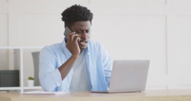 Kızgın Afrikalı adam çalışanlarla telefonda tartışıyor.