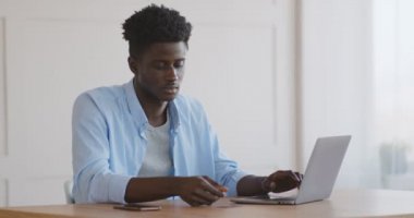 Afrikalı adam dizüstü bilgisayardan cep telefonundan SMS kodu giriyor