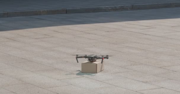 Drone kurier lecący z kartonowym pakietem w mieście — Wideo stockowe