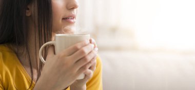 Kahve molası. Tanımlanamayan milenyum kızı elinde sıcak bir bardak içki tutuyor, yakın plan. Uzayı kopyala Panorama