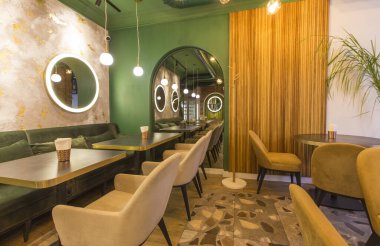 Masaları ve kanepeleri olan modern bir restoran, açık yeşil duvarlar.