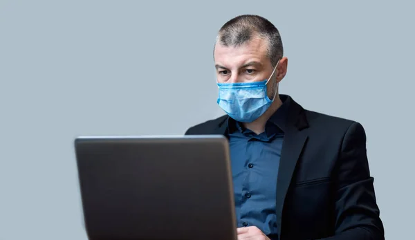 Підприємець працює з використанням ноутбука Комп'ютер носить захисну маску, студійний знімок — стокове фото