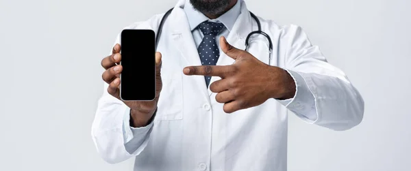 Przycięta przez afrykańskiego lekarza wskazującego na pusty ekran telefonu — Zdjęcie stockowe