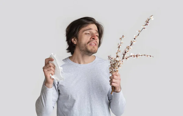 Allergy and bad feeling concept. Man holds flowers — Stock Photo, Image