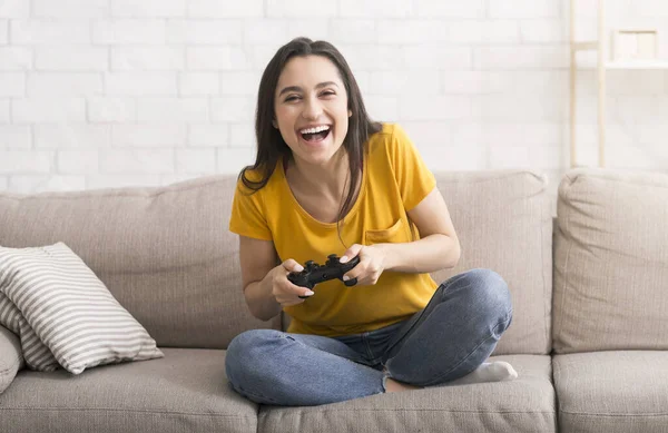 旅途愉快,待在家里消遣.兴奋的西班牙女孩，与控制器在室内沙发上玩电子游戏 — 图库照片