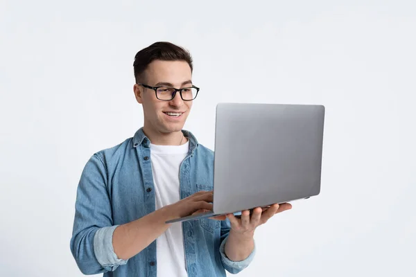 Freelancer trabaja en línea. Chico en gafas con portátil — Foto de Stock