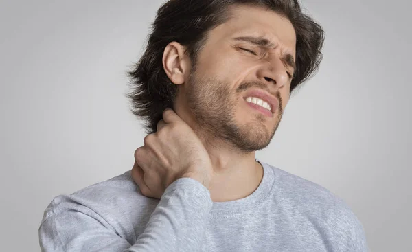 Man met pijnlijke uitdrukking wrijft zijn nek — Stockfoto