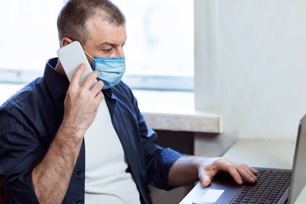Бізнесмен в медичній масці розмовляє по телефону працює вдома — стокове фото
