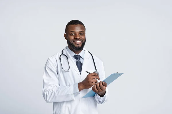 Smiling african therapist filling up medical forms — Stock Photo, Image