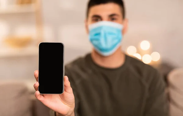 Man wearing surgical mask showing smart phone — Stock Photo, Image