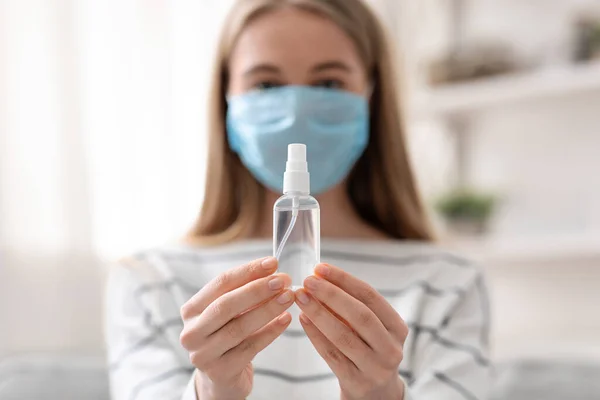 Jovem mulher em máscara protetora segurando gel higienizante nas mãos — Fotografia de Stock