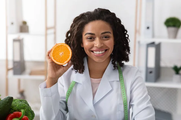 Ritratto di dottoressa sorridente con mezza arancia in mano — Foto Stock