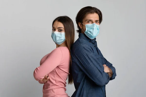 Άνδρας με αυτοπεποίθηση και γυναίκα με ιατρικές μάσκες να στέκονται πλάτη με πλάτη — Φωτογραφία Αρχείου