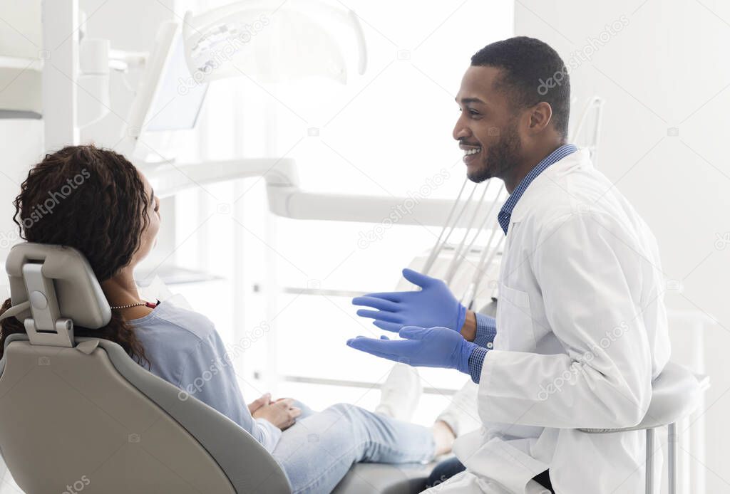 Friendly black dentist explaining patient treatment plan