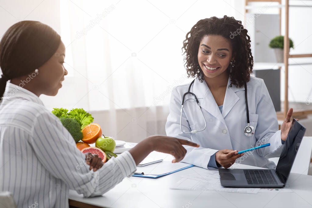 African woman dietologist consulting patient, using laptop