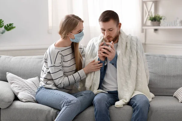 Zorgzame vrouw biedt warme thee aan haar zieke man thuis — Stockfoto