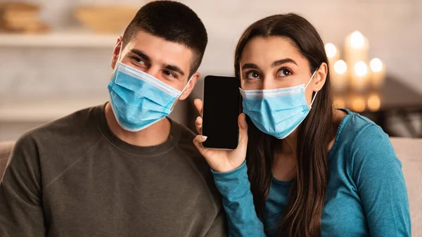 Pareja usando máscara quirúrgica usando teléfono inteligente — Foto de Stock