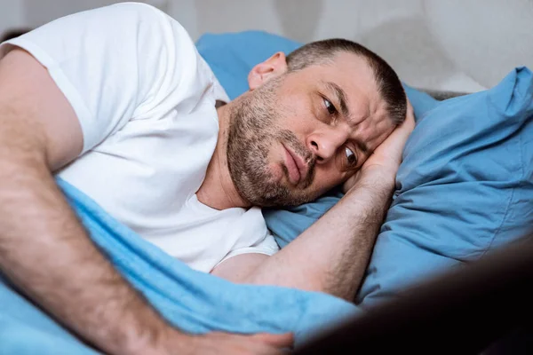 Hombre de mediana edad que tiene insomnio acostado en la cama en casa —  Fotos de Stock