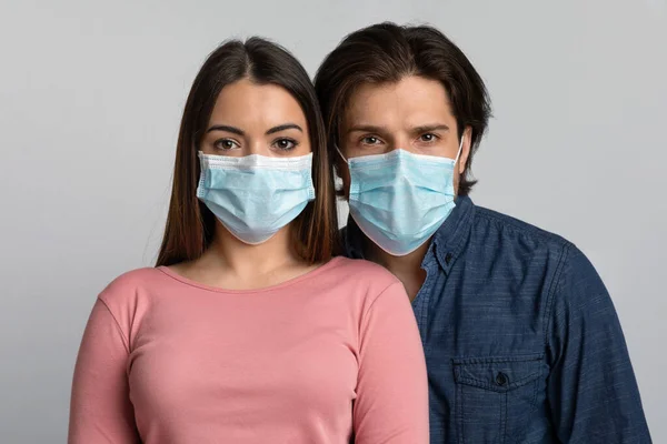 Portrait of young man and woman wearing medical masks looking at camera — Stock Photo, Image