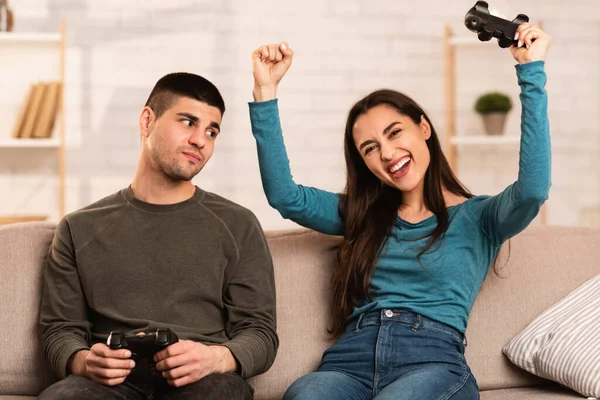 Pareja joven sentada en un sofá jugando videojuegos en línea — Foto de Stock