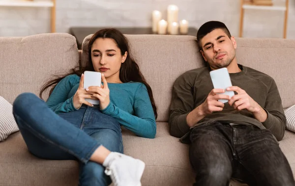 Paar met mobiele telefoons op de bank — Stockfoto