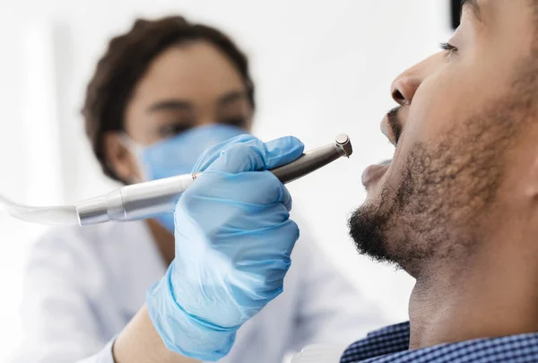 Close up of female dentist treating black man teeth