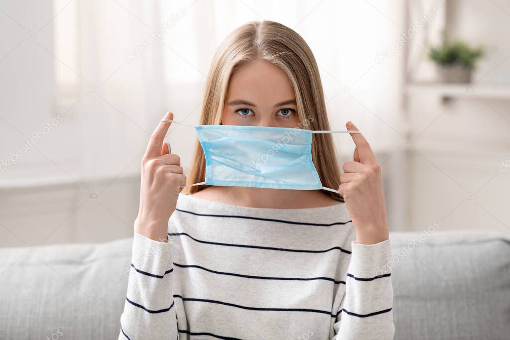 Responsible girl putting on medical protective mask before going out
