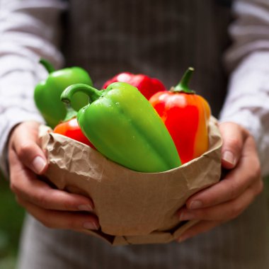Müşteri için kırmızı biberli kağıt poşet tutan adam.