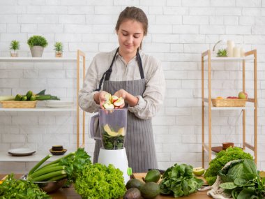 Blender 'da detoks smoothie hazırlayan genç kadın.